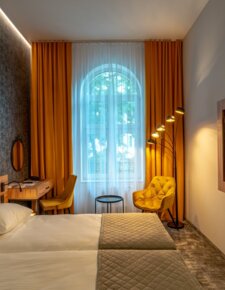 Cozy hotel room with a large window overlooking Krakow’s Kazimierz, bathed in warm lighting