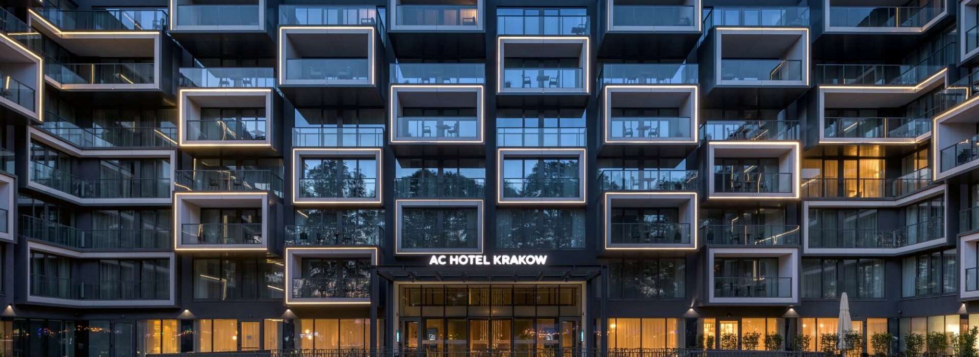 Elegancka fasada AC Hotel Kraków by Marriott widziana po zmroku, z subtelnym oświetleniem