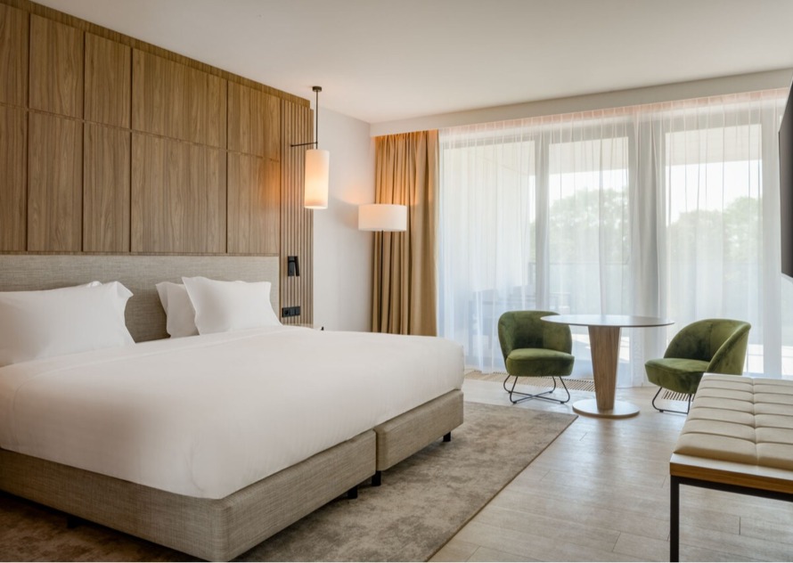 A bright hotel room with wood and green accents