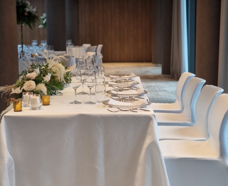 A Table Decorated in White with a Tablecloth and Fresh Flowers