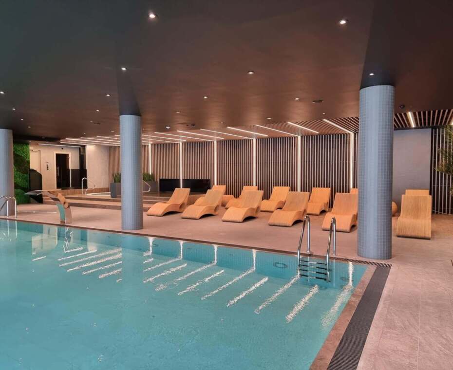 Przestrzeń basenowa z wygodnymi leżakami, idealna do relaksu i odpoczynku