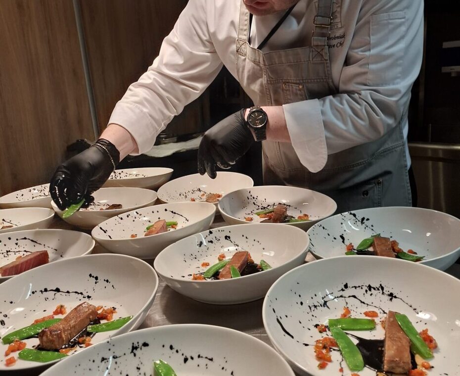 Kucharz pracujący przy wydawaniu – precyzyjnie komponujący dania tuż przed ich podaniem.