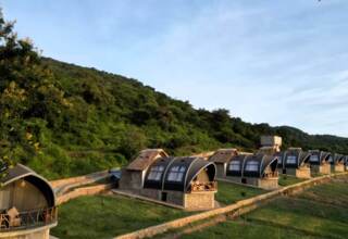 Row of eco-friendly stone cottages with curved roofs and private balconies nestled on a hillside with lush greenery
