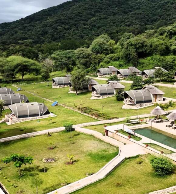 Eco-friendly lodge with modern tented suites surrounded by lush greenery and hill views, featuring a pool with shaded loungers