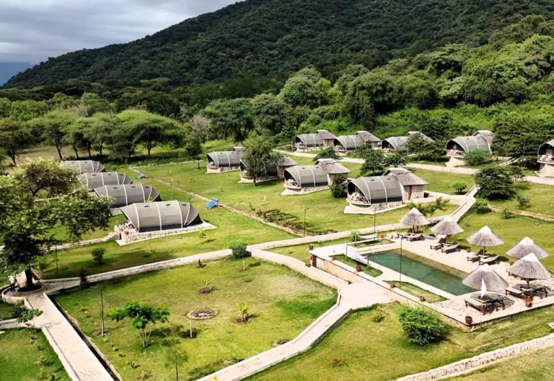Eco-friendly lodge with modern tented suites surrounded by lush greenery and hill views, featuring a pool with shaded loungers