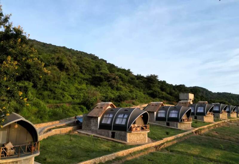 Row of eco-friendly stone cottages with curved roofs and private balconies nestled on a hillside with lush greenery