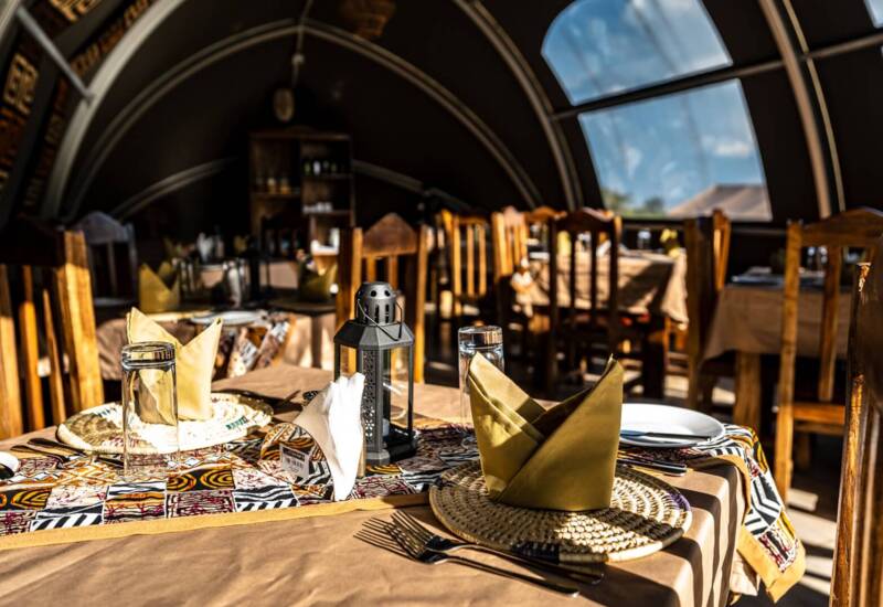 Cozy dining area with rustic wooden chairs and tables set with woven placemats, folded napkins, and decorative lanterns inside arched windows