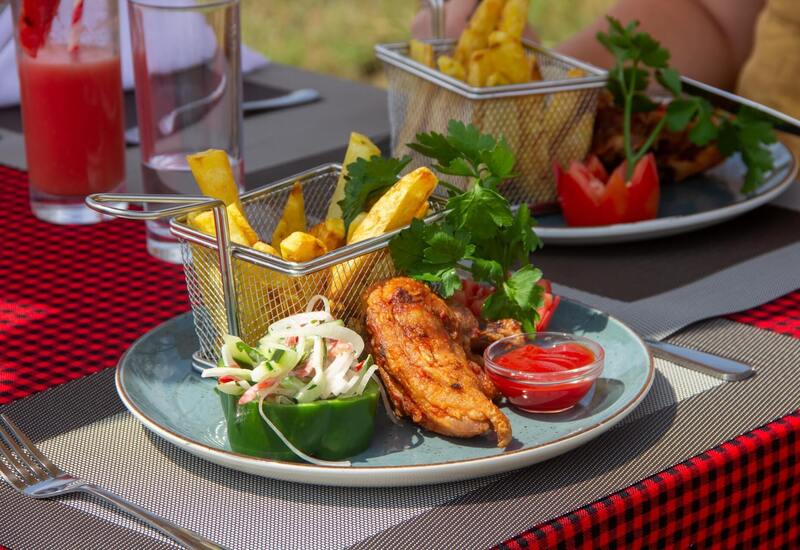 Crispy chicken wings with fries in mini baskets, fresh bell-pepper salad and ketchup served on an outdoor dining table