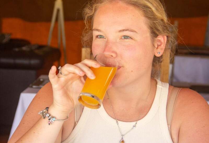Guest sipping fresh orange juice at hotel breakfast table with plated morning meal and cozy indoor dining ambiance