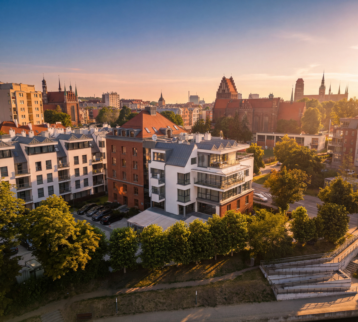 Nowoczesne apartamenty i hotel z balkonami i tarasami na dachu, słoneczny widok na zabytkową ceglaną katedrę
