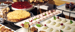 Dessertbuffé med utvalg av bakverk: hvite mousse-domer med bringebær og mynte, rosa makroner, smuldrekake og små sjokoladeovertrukne kaker