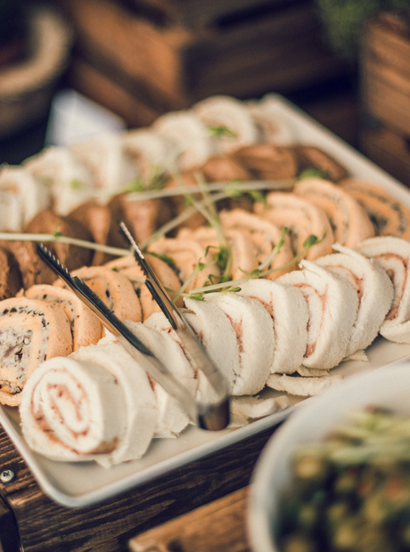 Fat med rullede fingermatkanapéer, pyntet med mikrogrønt og serveringstang på buffet