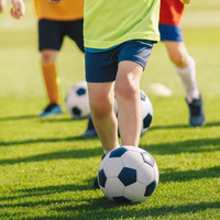 Dzieci grające w piłkę nożną na trawiastym boisku podczas hotelowego programu rekreacyjnego dla najmłodszych.