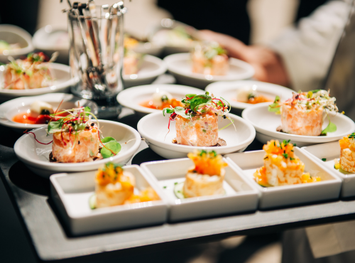 Eleganckie przystawki z delikatnym nadzieniem i świeżymi ziołami podane na białych talerzach podczas hotelowego bankietu.