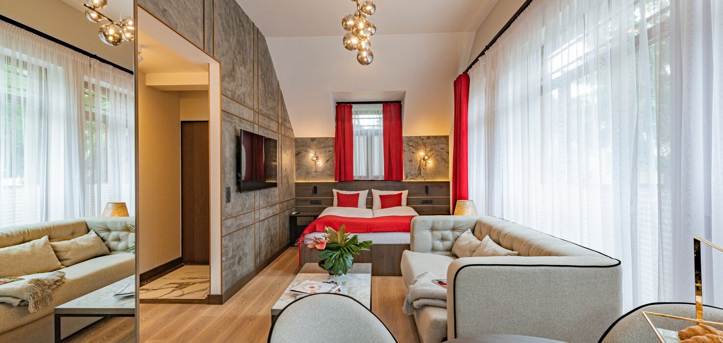 Przestronny apartament zawierający część dzienną z sofą, część jadalną ze stołem i łóżko we wnęce.