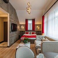 A long room with a double bed, sofa, coffee table, and large window.