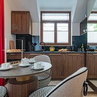 A kitchenette along the wall with a window and a round table with three comfortable chairs.