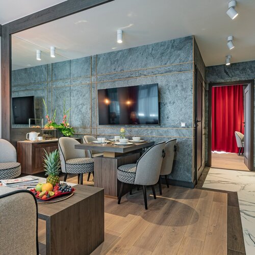 Living room with a sofa, coffee table, dining area and a TV on the wall.