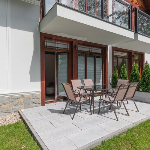 A small terrace with a table and six garden chairs.