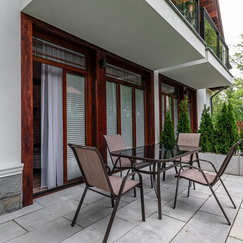 A small terrace with a table and six garden chairs.