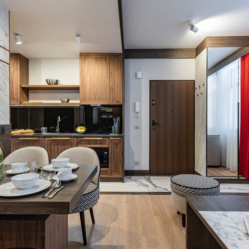 Living area with sofa, coffee table and television, visible wooden kitchen furniture in the backgrou