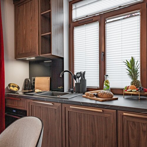 Kitchenette with dark cupboards, sink and electric kettle.