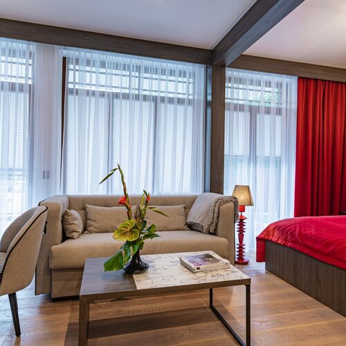 Sofa with coffee table against large windows, visible fragment of bed.