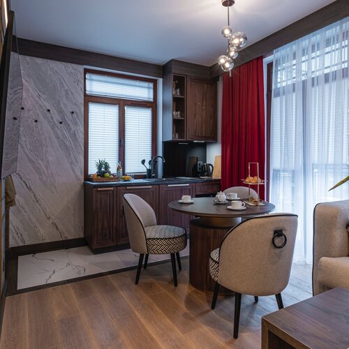 Dining area with a round table, chairs and a kitchenette with a visible window.