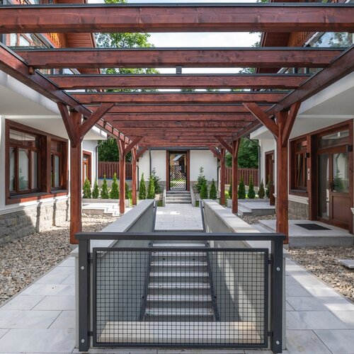 A wooden pergola between buildings above the stairs leading underground.