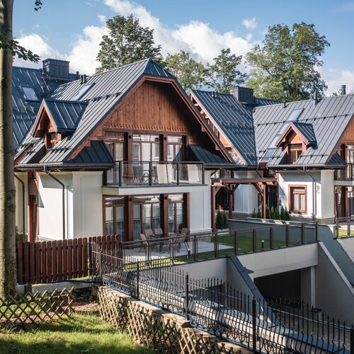 Two modern two-storey houses in the Zakopane style with garages underneath.