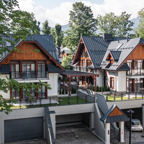 Two modern two-storey houses in the Zakopane style with garages underneath.