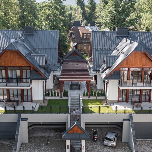 Two modern two-storey houses in the Zakopane style with garages underneath.
