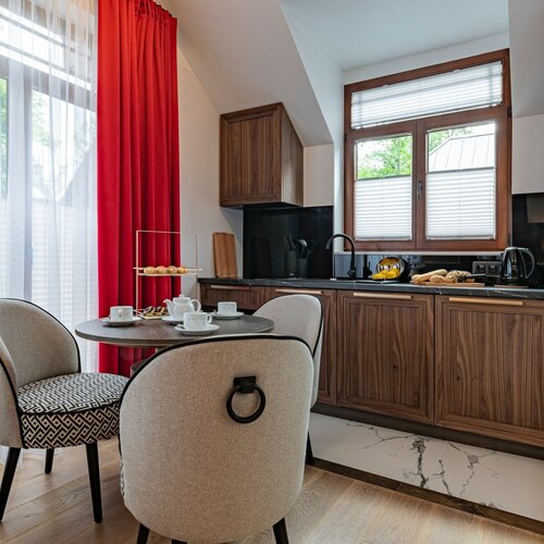 View of the kitchenette with wooden cabinets, a window, a round table and chairs.