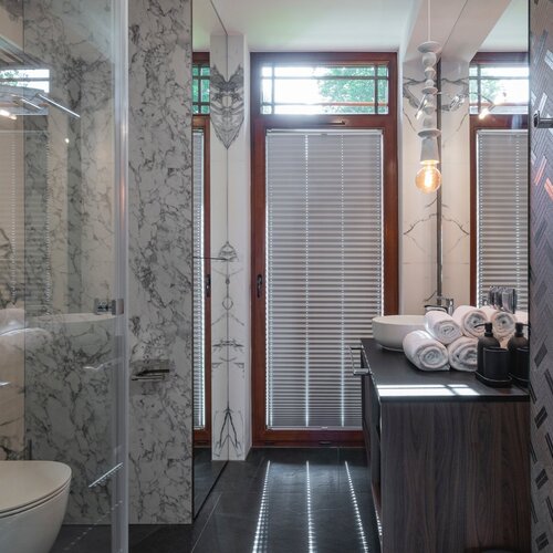 Bathroom with shower, washbasin and large mirror on the wall.