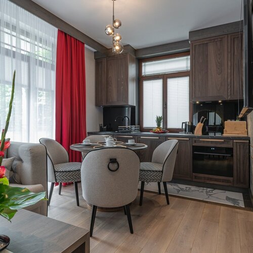 Dining table with four chairs next to the kitchenette and large window.