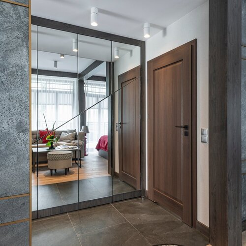 Hallway with a large mirror and a view of the living area of the flat.