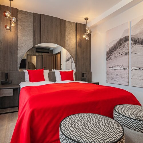 Double beds and two pouffes in an elegant room.