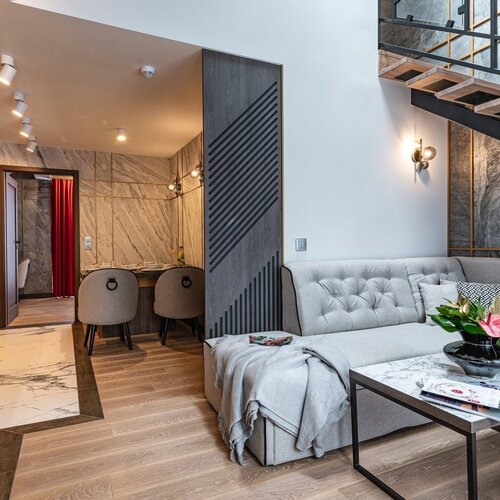 A room with a light-colored sofa and access to the dining room.