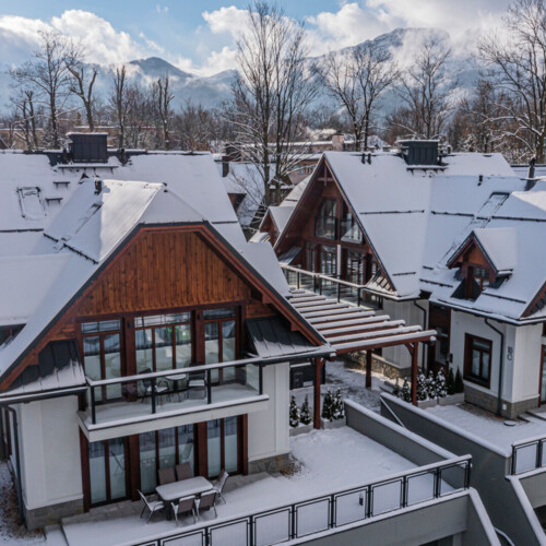 A view of two modern houses in the Zakopane style covered with snow.