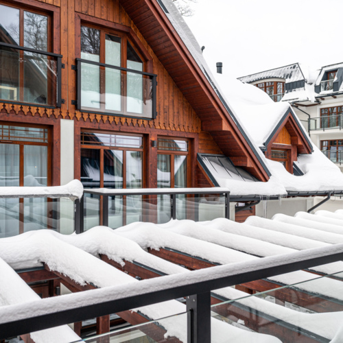 A view of a modern house in the Zakopane style covered with snow.