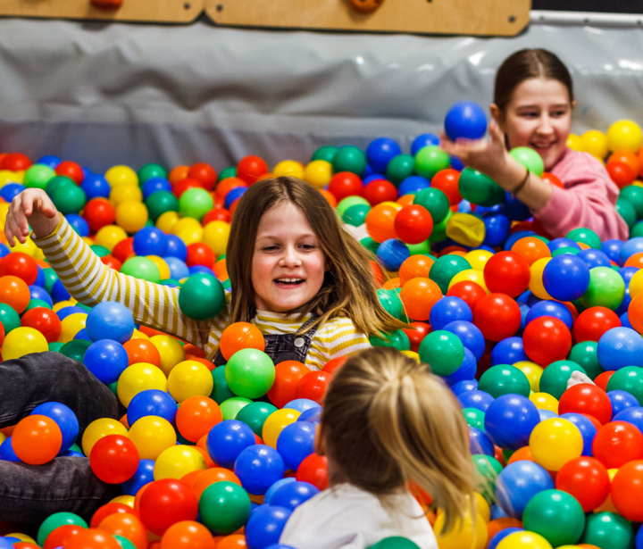 Dzieci bawiące się w miękkim basenie z kolorowymi piłkami na hotelowym placu zabaw.