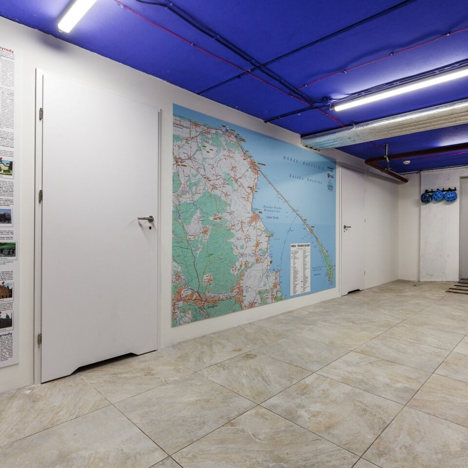 Hotelbereich mit großer Küstenkarte und Infos zu Sehenswürdigkeiten, blau gestrichene Decke und aufbewahrte Fahrradhelme