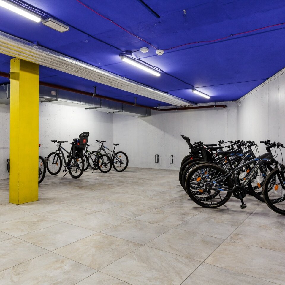 Geräumiger unterirdischer Fahrradverleih mit modernen Helmen und sicherem Abstellplatz für Gastfahrräder.