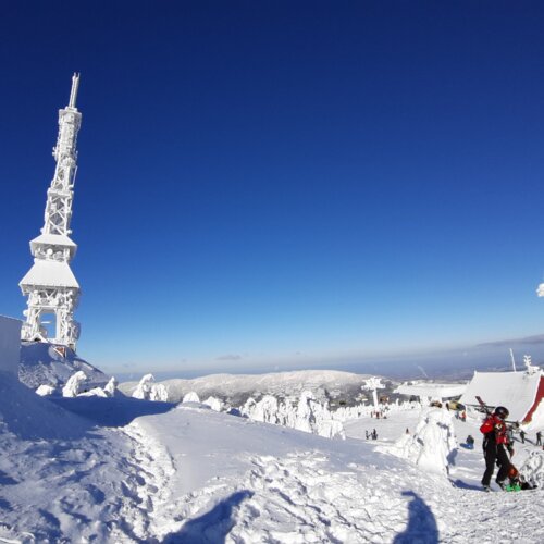 Górski ośrodek narciarski z zaśnieżonymi szczytami, wyciągami, budynkiem i narciarzem na stoku