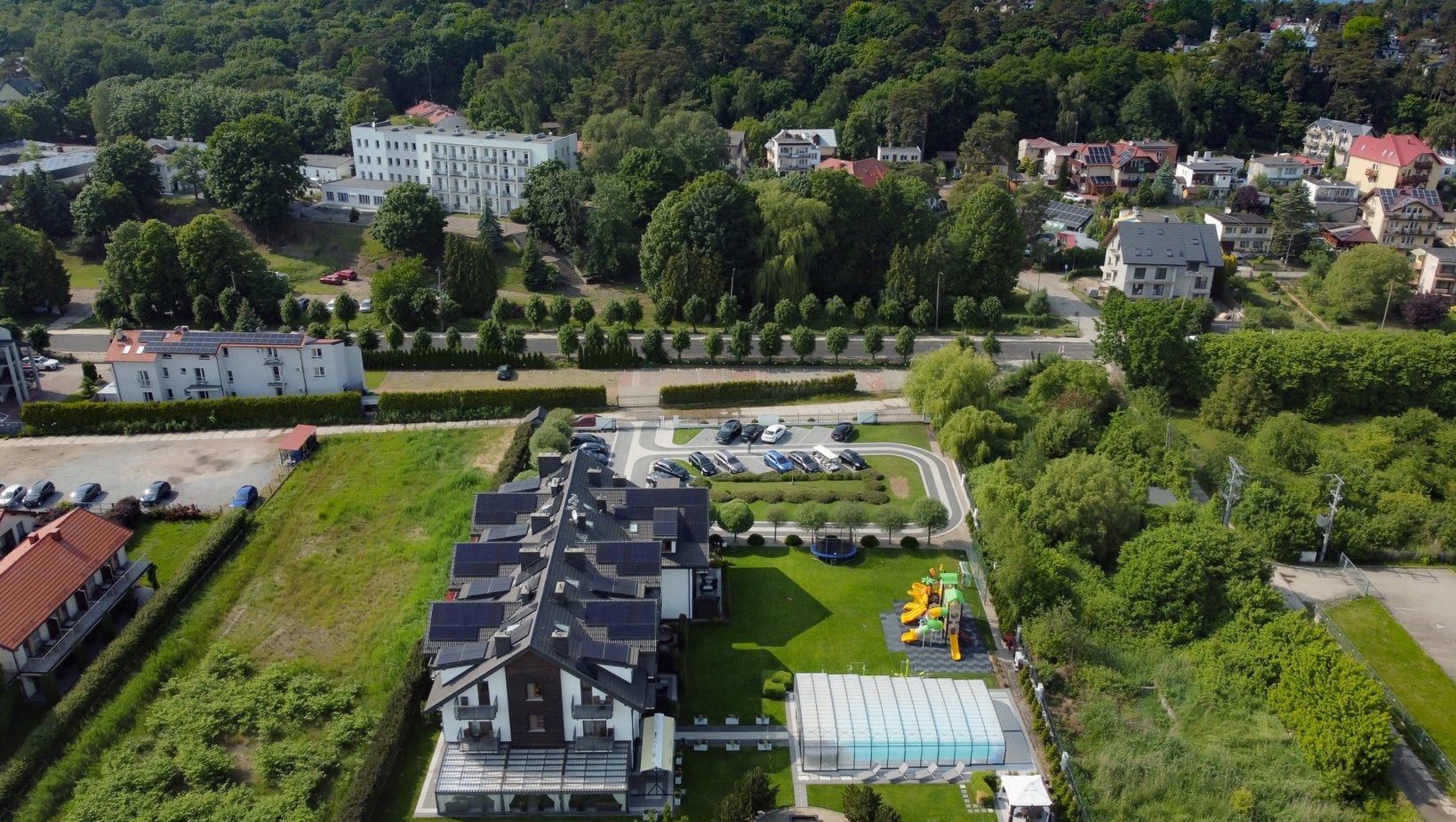 Butikowy hotel z krytym basenem, placem zabaw z kolorowymi zjeżdżalniami, parkingiem, balkonami i widokiem na las