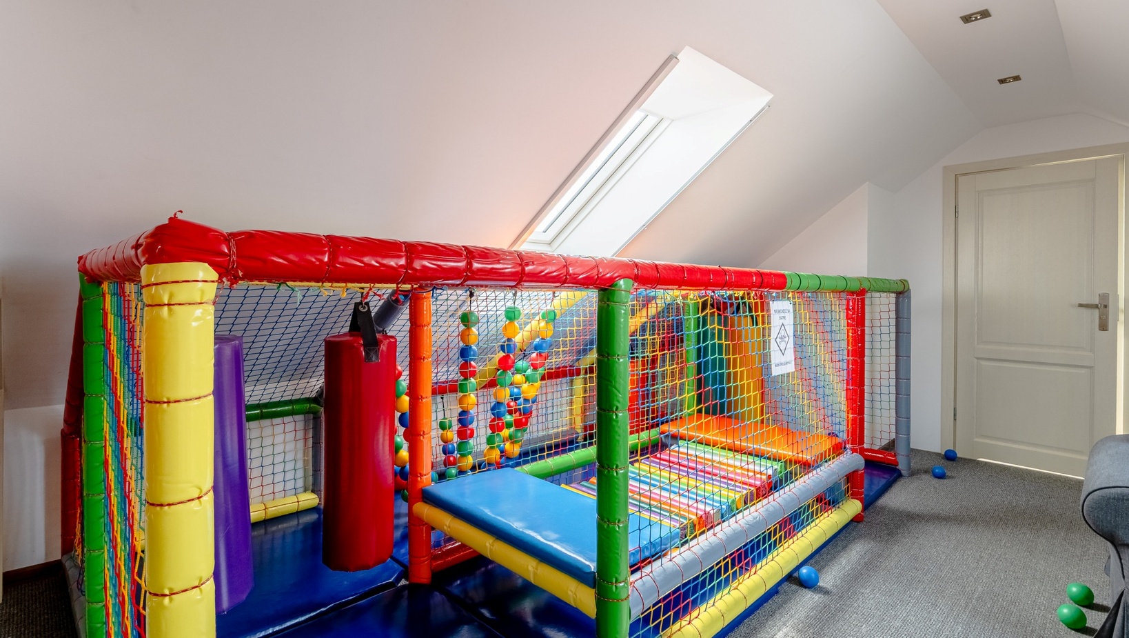 Kolorowy wewnętrzny plac zabaw na poddaszu z miękkimi przeszkodami, piłeczkami i strefą zabaw dla dzieci