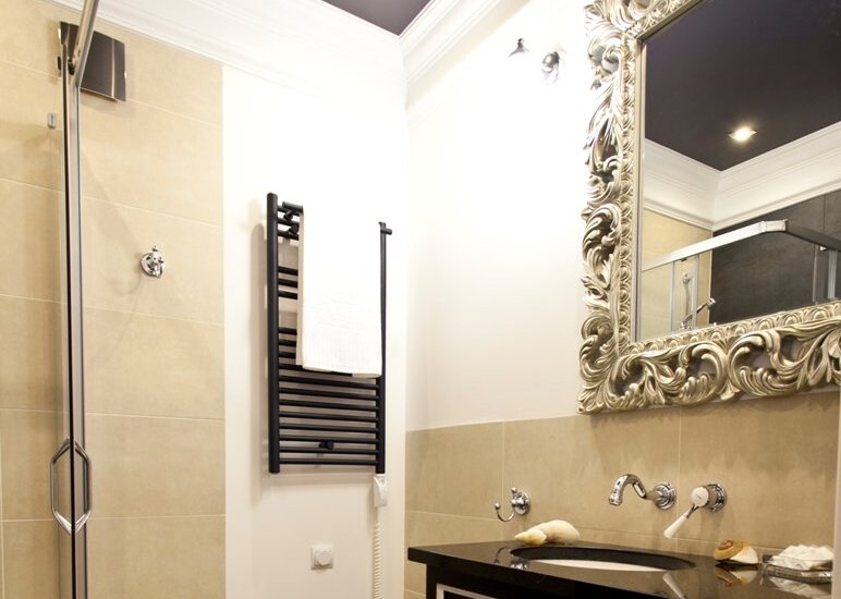 Luxurious ensuite bathroom with glass walk-in shower, ornate mirror, black vanity with marble top and heated towel rail