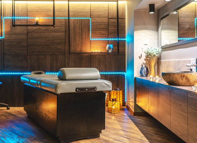 Moderner Spa-Raum mit komfortabler Massageliege, stimmungsvoller Beleuchtung und warmen Holzakzenten