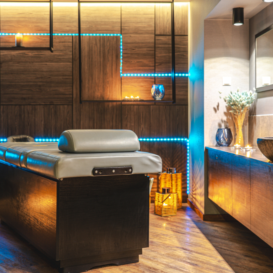 Moderner Spa-Raum mit komfortabler Massageliege, stimmungsvoller Beleuchtung und warmen Holzakzenten