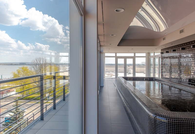 Kryty basen spa wykończony mozaiką, świetlik, panoramiczne okna i taras nad jeziorem z leżakami